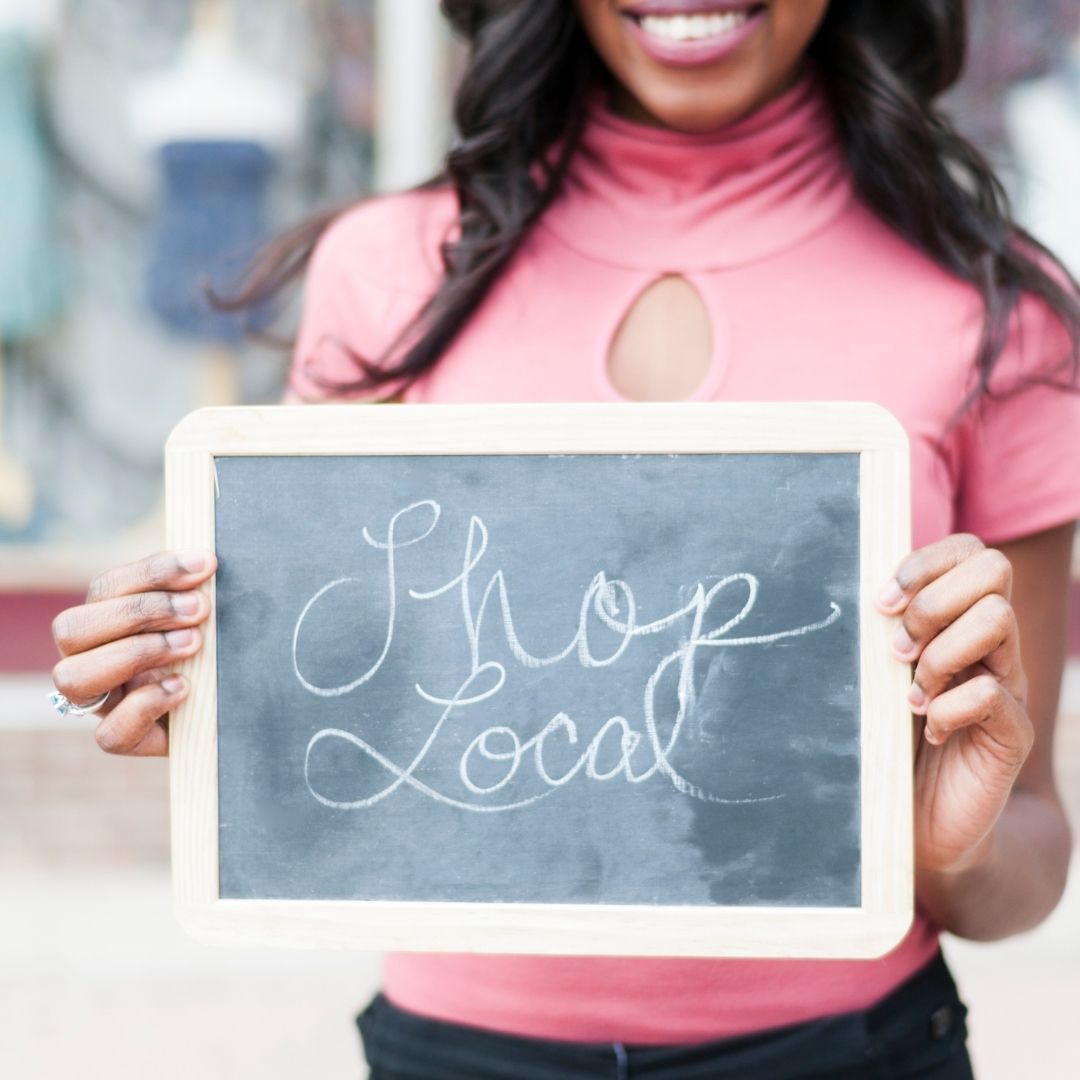 Woman holding a "Shop Local" sign